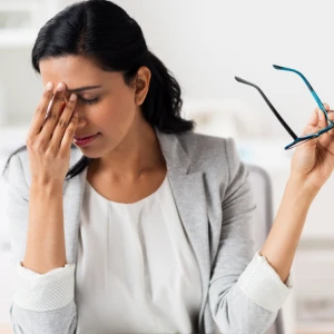 A young woman holding her hand to her pained eyes